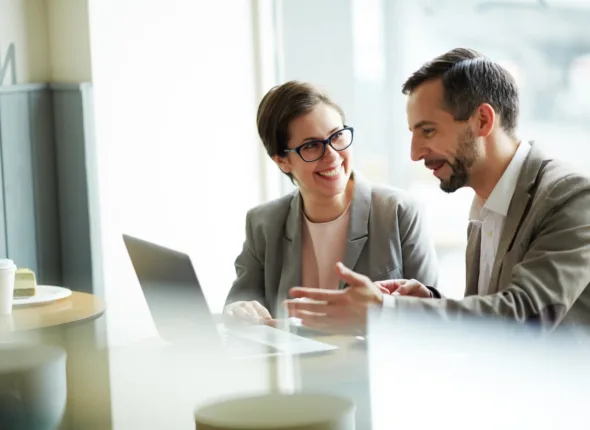 Un uomo e una donna che conversano di fronte a un computer